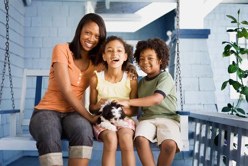 A woman and two children sitting on a porch swing.