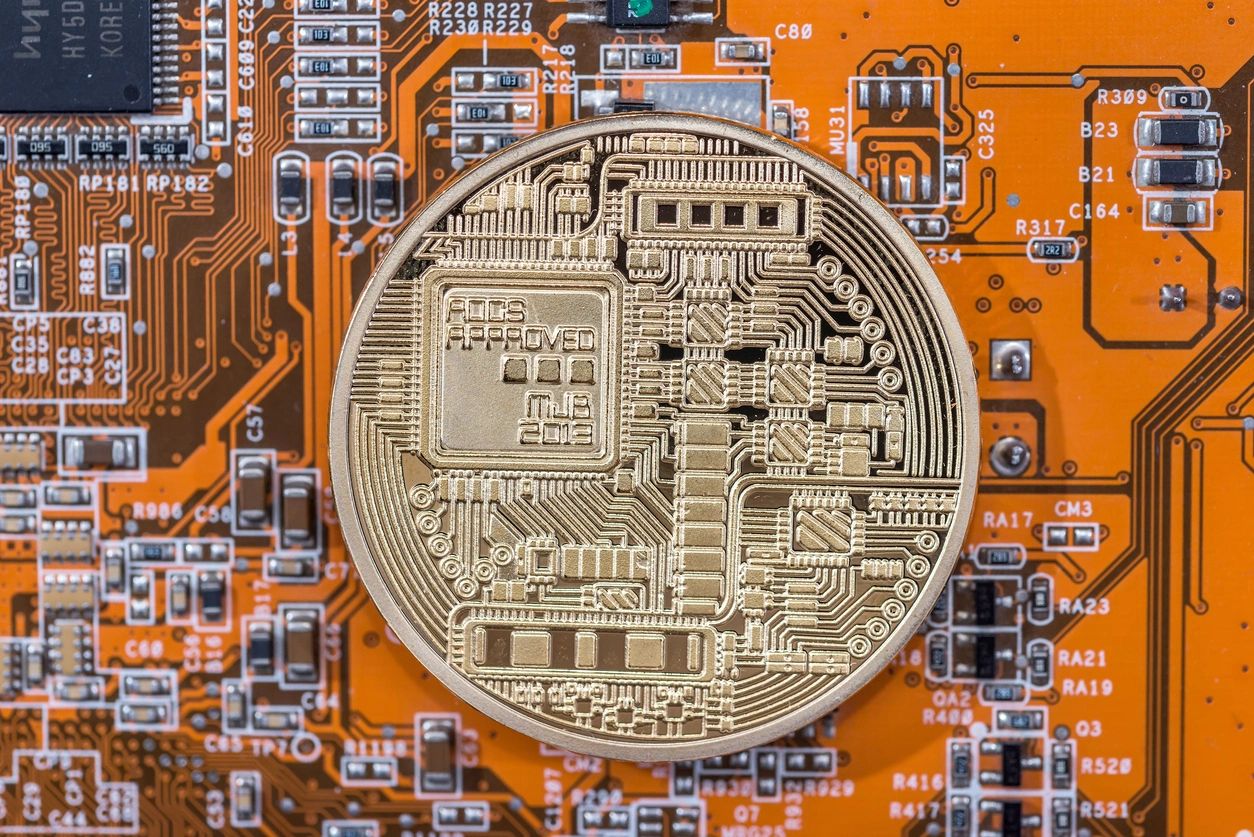 A coin is shown on top of an electronic circuit board.