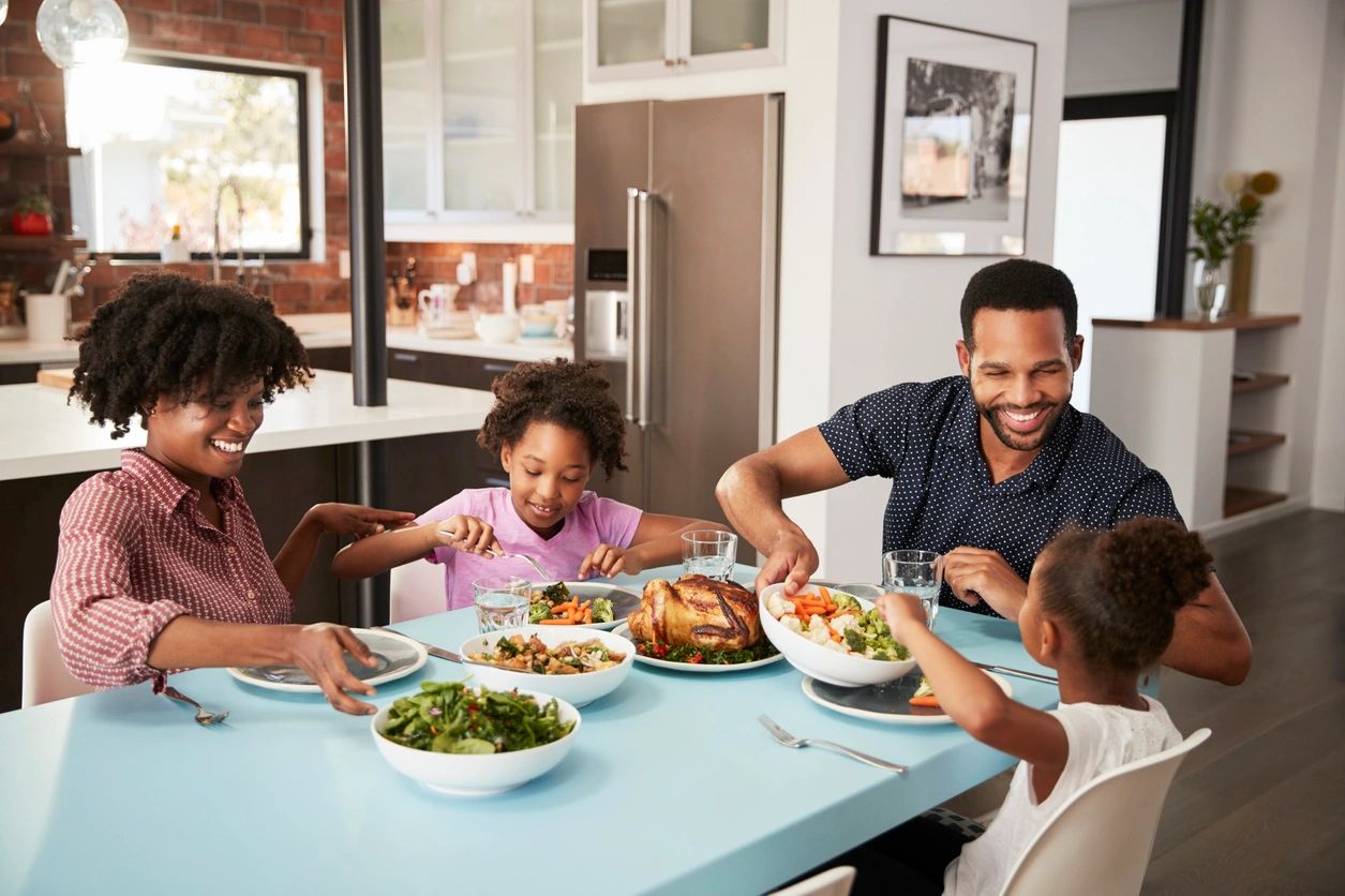 A family sitting at the table eating dinner.