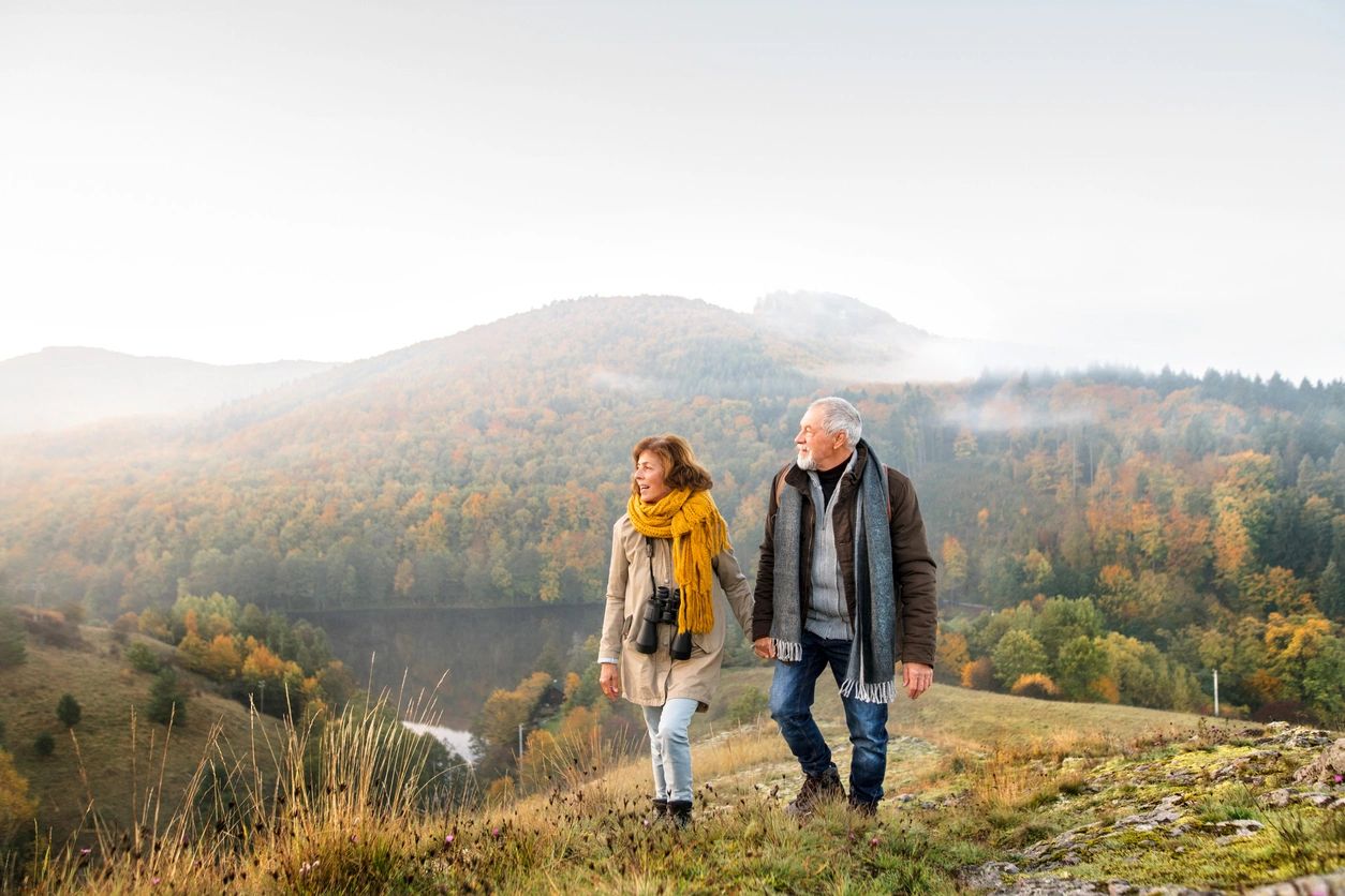 A man and woman walking on top of a hill.