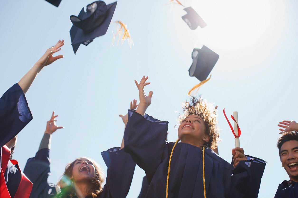 A group of people throwing their caps in the air.