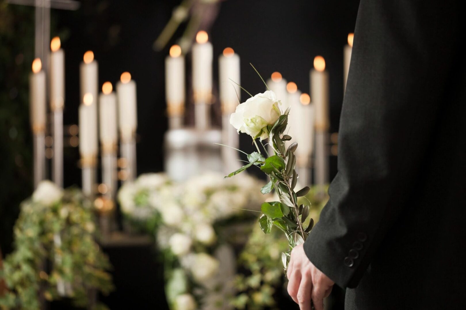 A person holding flowers in front of candles.