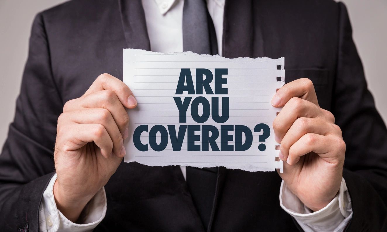 A man holding up a sign that says are you covered