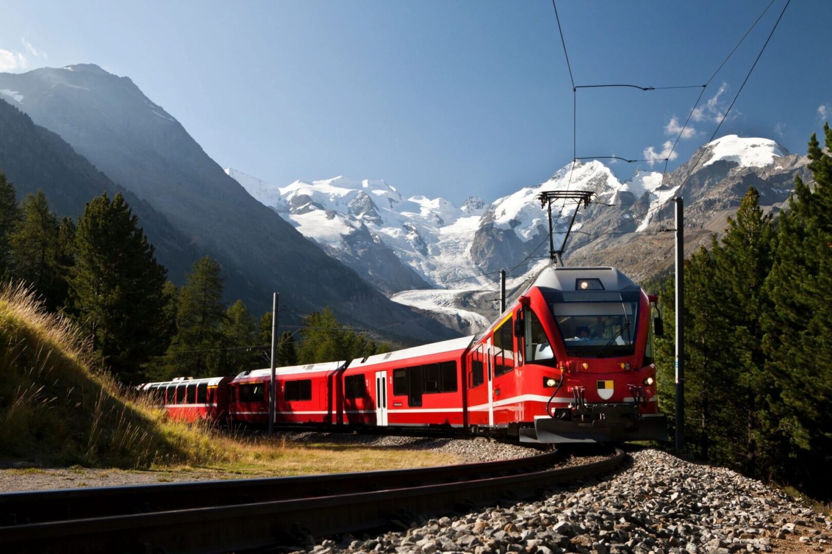 A train is traveling down the tracks near some mountains.