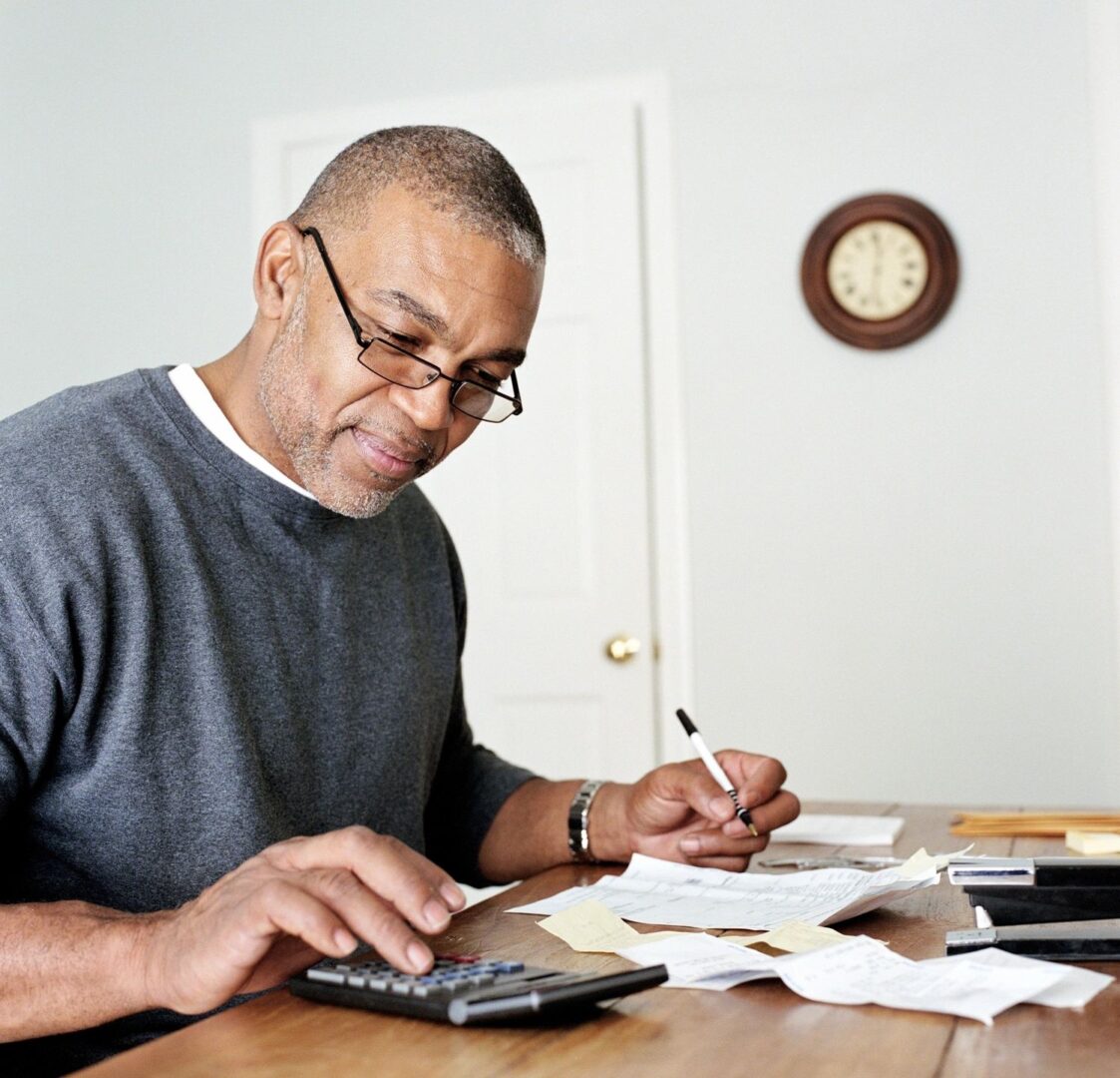 A man sitting at the table with papers and a calculator.