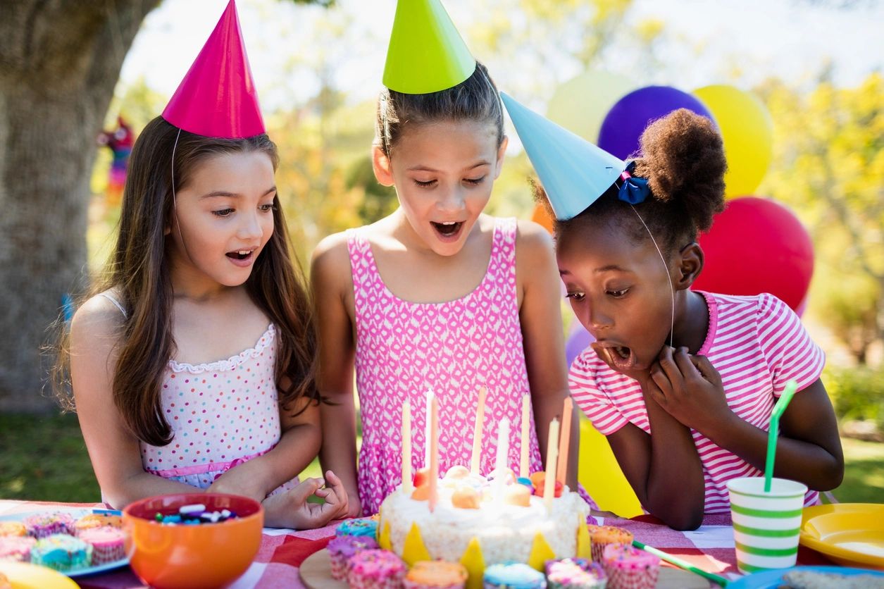 A group of girls blowing out candles on a cake.