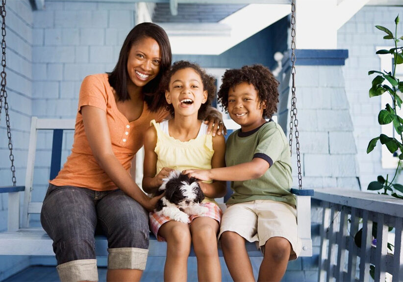 A woman and two children sitting on a porch swing.