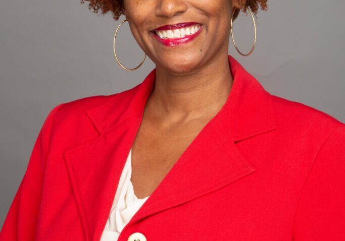 A woman in red jacket smiling for the camera.