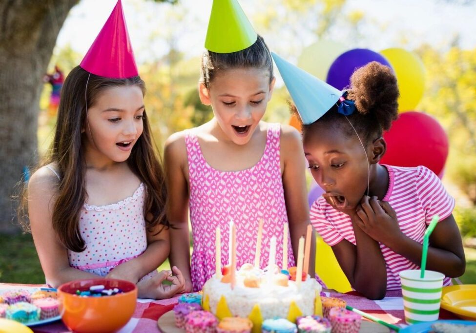 A group of girls blowing out candles on a cake.