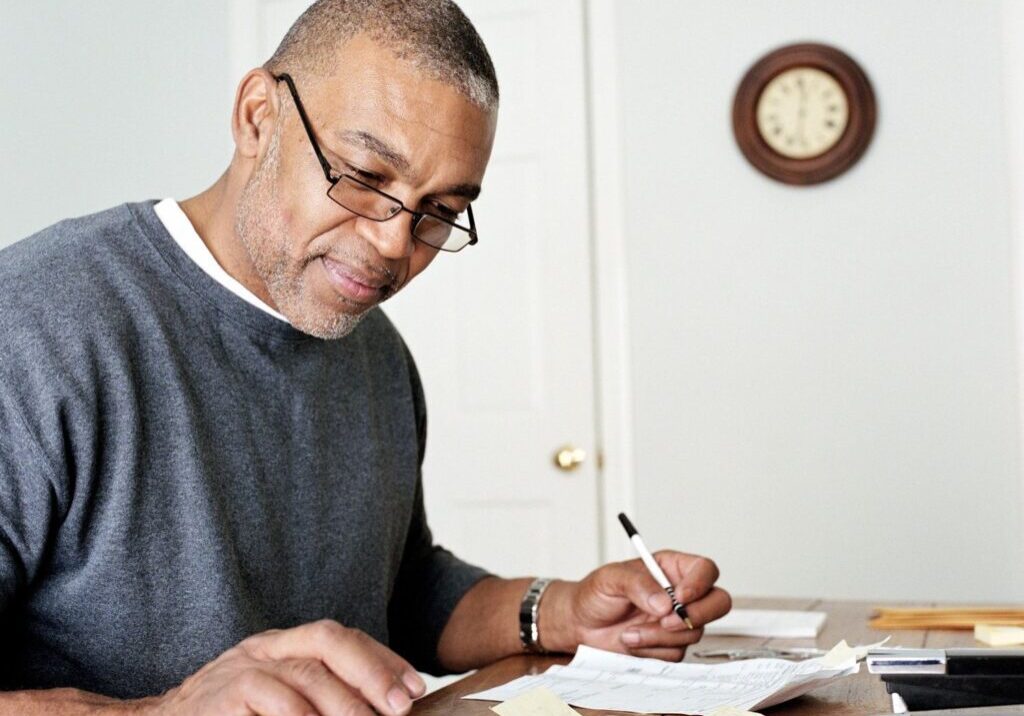 A man sitting at the table with papers and a calculator.