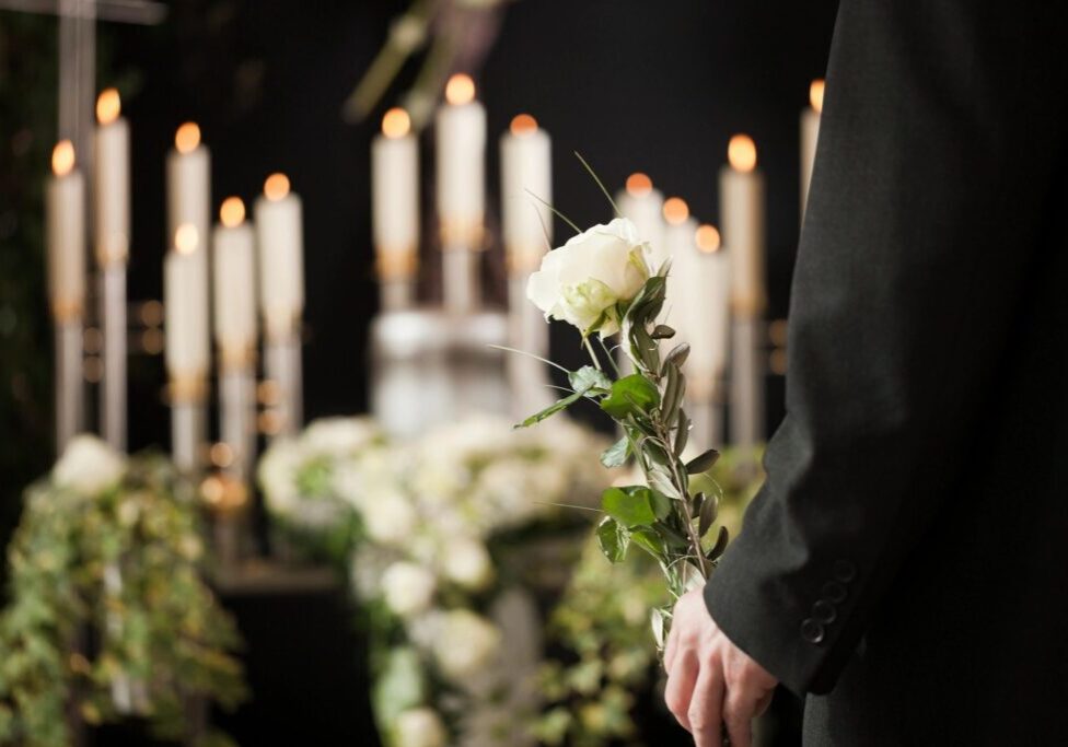 A person holding flowers in front of candles.