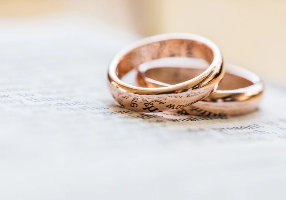 Two gold wedding rings sitting on top of a paper.