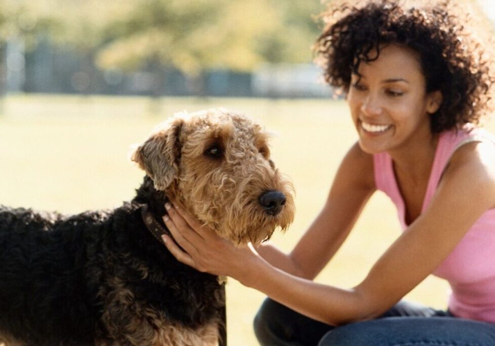 A woman petting her dog in the park.