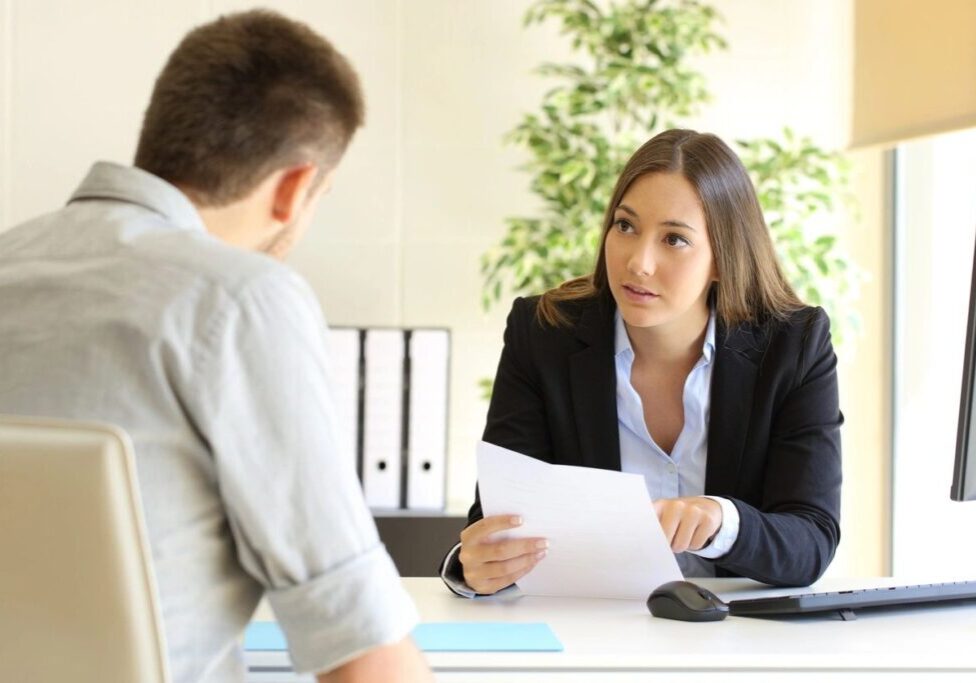 A woman is interviewing a man in an office setting.