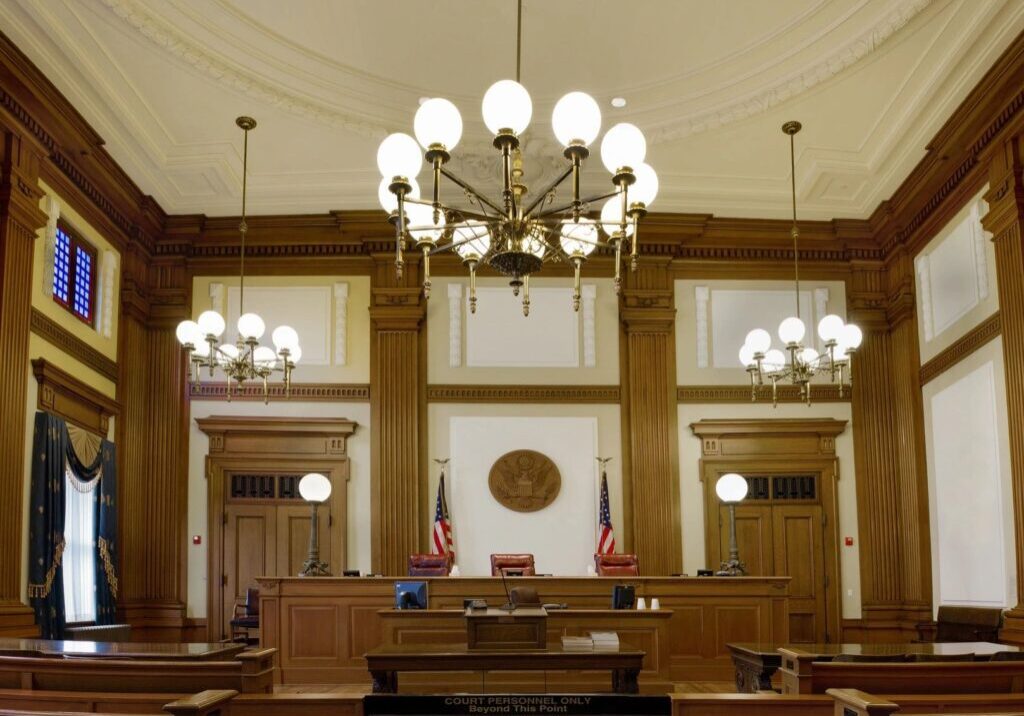 A courtroom with many wooden benches and chandeliers.