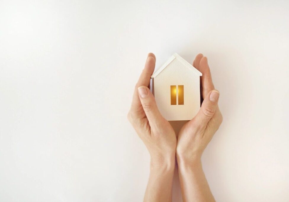 A person holding a small house in their hands.