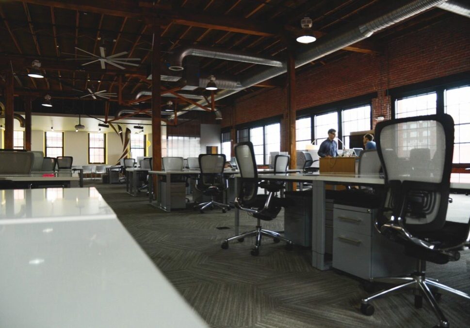 A large open office with many desks and chairs.