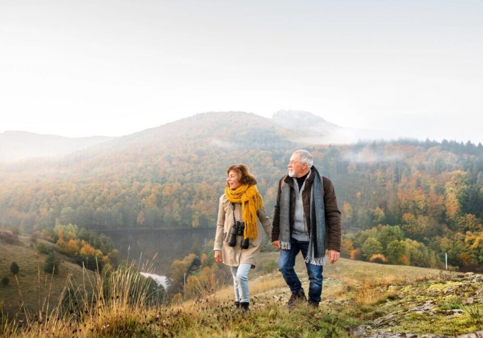 A man and woman walking on top of a hill.